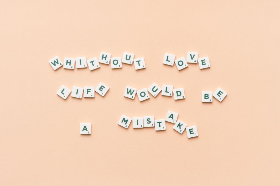 Imagem com peças de scrabble formando a mensagem 'Without love life would be a mistake', simbolizando reflexão sobre o amor e o significado da vida.