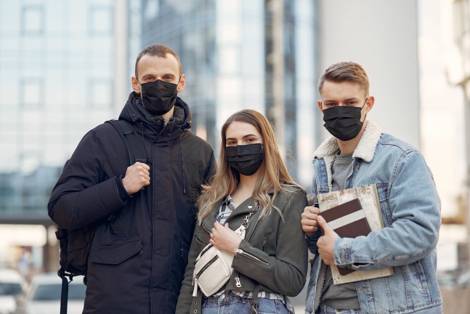 Grupo de jovens usando máscaras faciais na rua, simbolizando a adaptação às novas formas de convivência durante a pandemia.