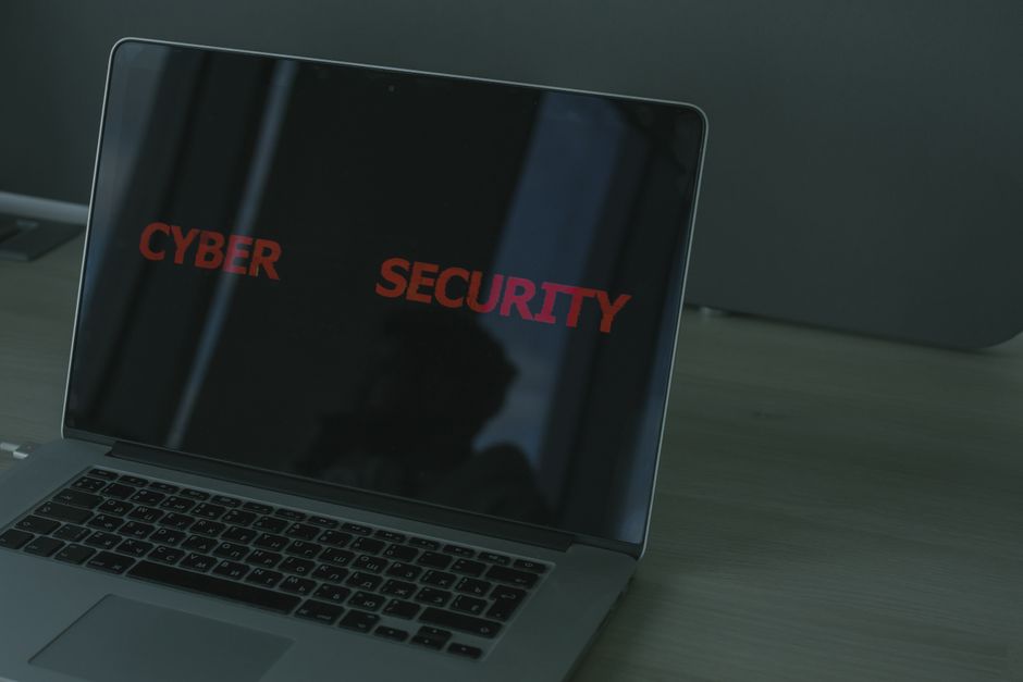 Tela de laptop exibindo a palavra 'CYBER SECURITY' em um ambiente de trabalho, destacando a importância da segurança digital.