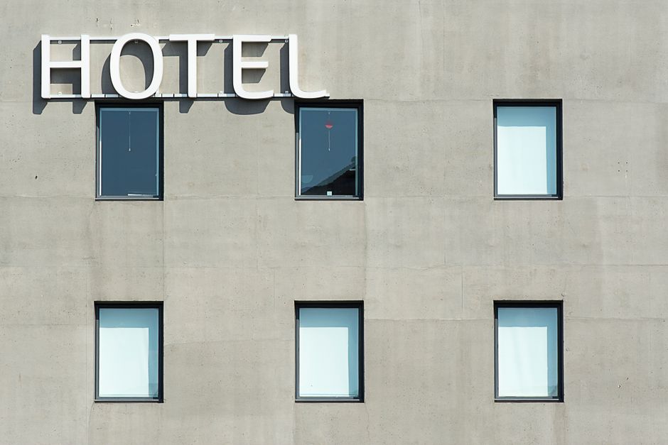 Imagem de um edifício com uma fachada de concreto e janelas retangulares, com o sinal de 'HOTEL' em destaque na parte superior, ideal para artigos sobre infraestrutura de hotéis ou hotelaria moderna.