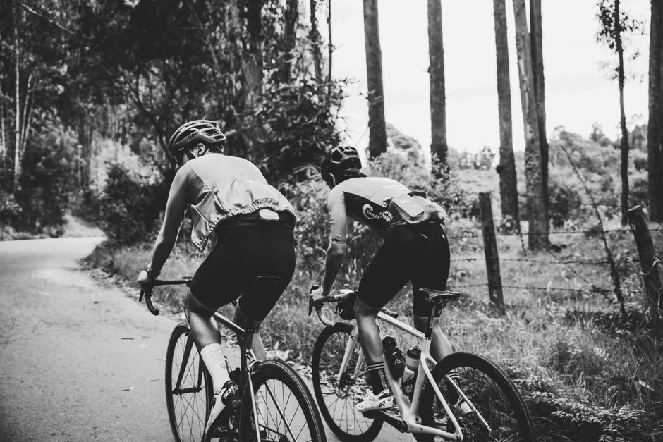 Dupla de ciclistas aproveitando uma trilha na floresta para exercícios ao ar livre e contato com a natureza.