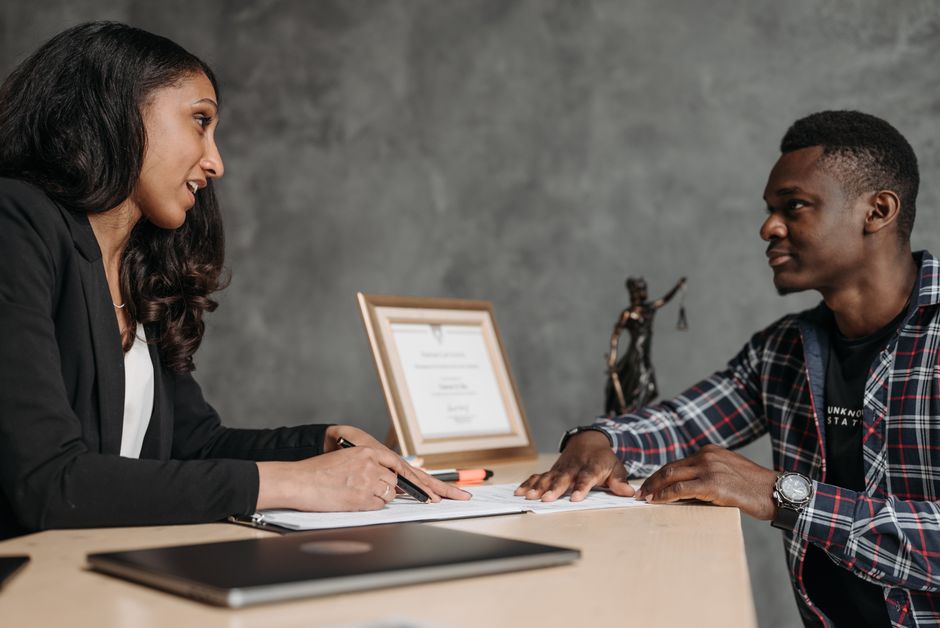 Duas pessoas em uma entrevista de emprego ou reunião profissional, demonstrando interação e diálogo em um ambiente de escritório.