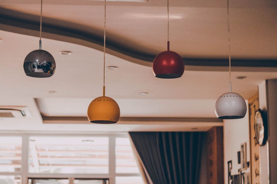 Luminárias coloridas penduradas no teto de um ambiente residencial, criando um ambiente acolhedor e moderno para um blog sobre decoração e design de interiores.