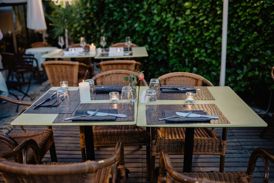 Imagem de um espaço ao ar livre preparado para um jantar íntimo, com mesas decoradas e ambientes acolhedores, ideal para artigos sobre restaurantes, gastronomia ou eventos ao ar livre.