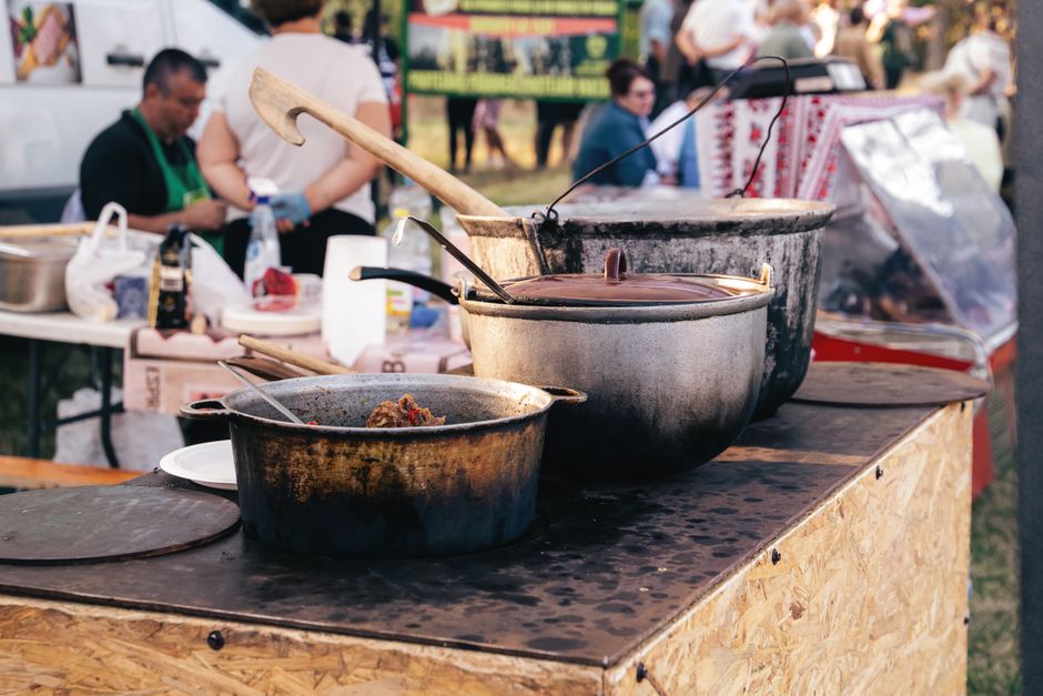 Cena de uma barraca de comida ao ar livre, destacando panelas e utensílios utilizados na preparação de pratos tradicionais em um evento ao ar livre.