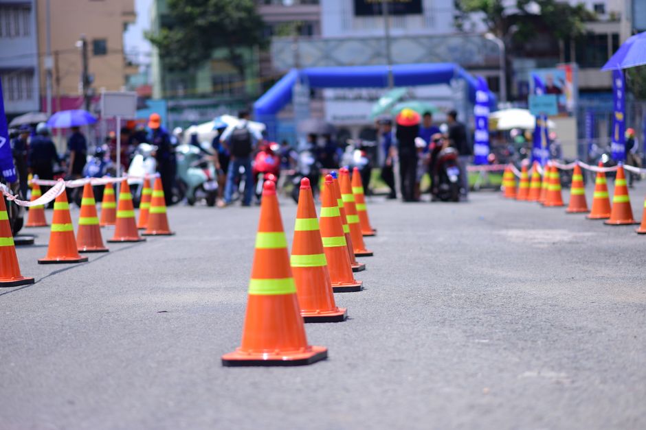 Imagem de uma área fechada ao trânsito com cones de isolamento e um público ao fundo, indicando evento ou controle de acesso na cidade.