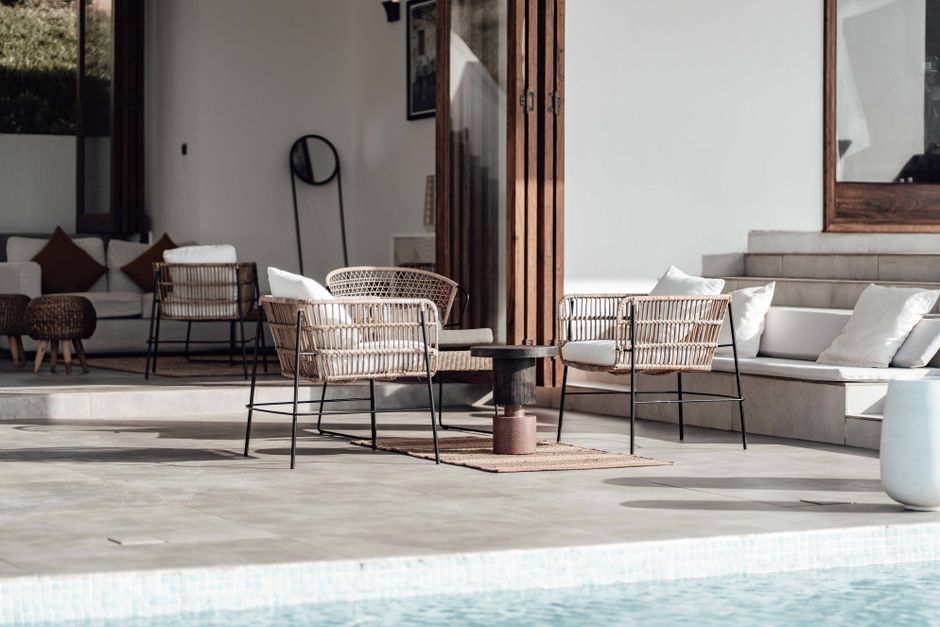 Espaço ao ar livre com área de convívio com cadeiras de vime e poltronas de tecido, ideal para relaxar e socializar em um ambiente bem iluminado e decorado de forma moderna.