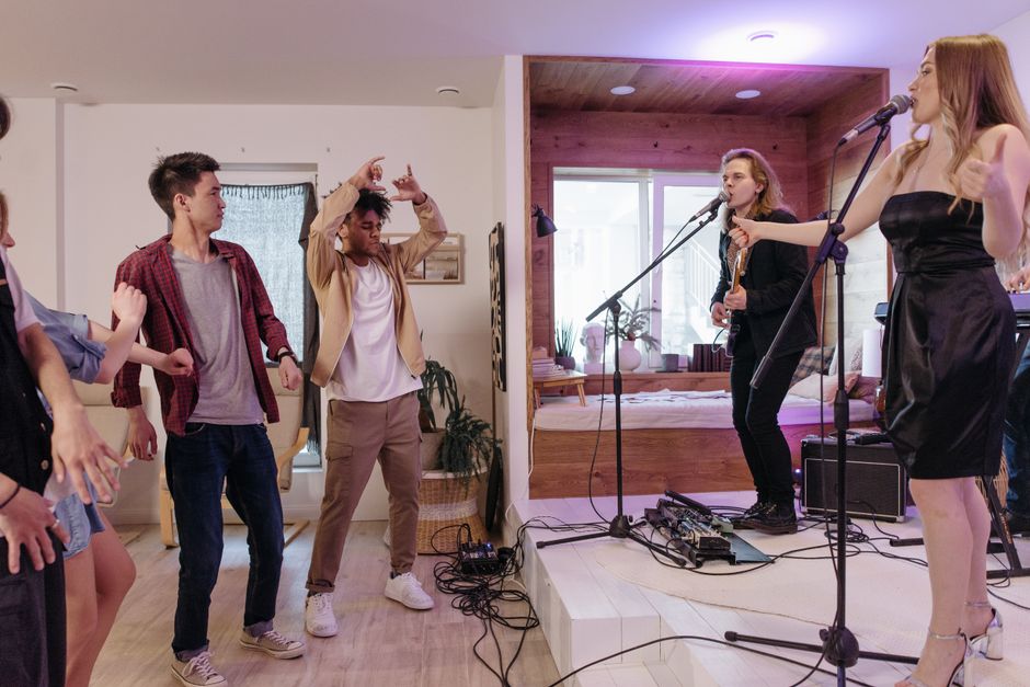 Jovens participando de uma atividade musical ao vivo em um ambiente interno acolhedor, com destaque para o momento de interação e entretenimento.
