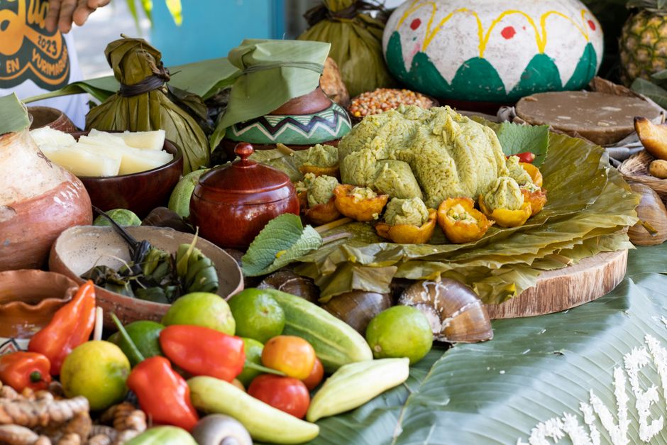 Arranjo de alimentos tradicionais mexicanos com frutos, verduras e doces, decorado para celebrações culturais.
