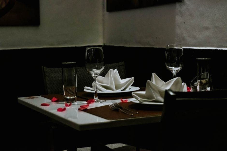 Mesa de jantar cuidadosamente preparada com talheres, copos e guardanapos em um ambiente elegante, ideal para um jantar romântico ou celebração especial.