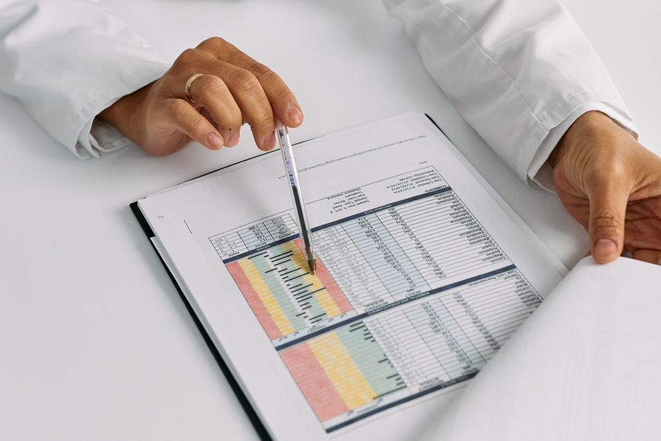 Pessoa analisando uma planilha financeira com destaque para dados coloridos e gráficos, evidenciando controle financeiro e tomada de decisão.