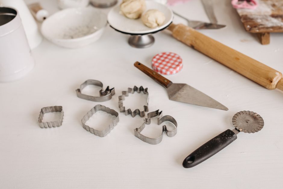 Imagem de utensílios de confeitaria e ferramentas de cozinha em uma bancada, sugerindo preparo de alimentos ou decoração de bolos.