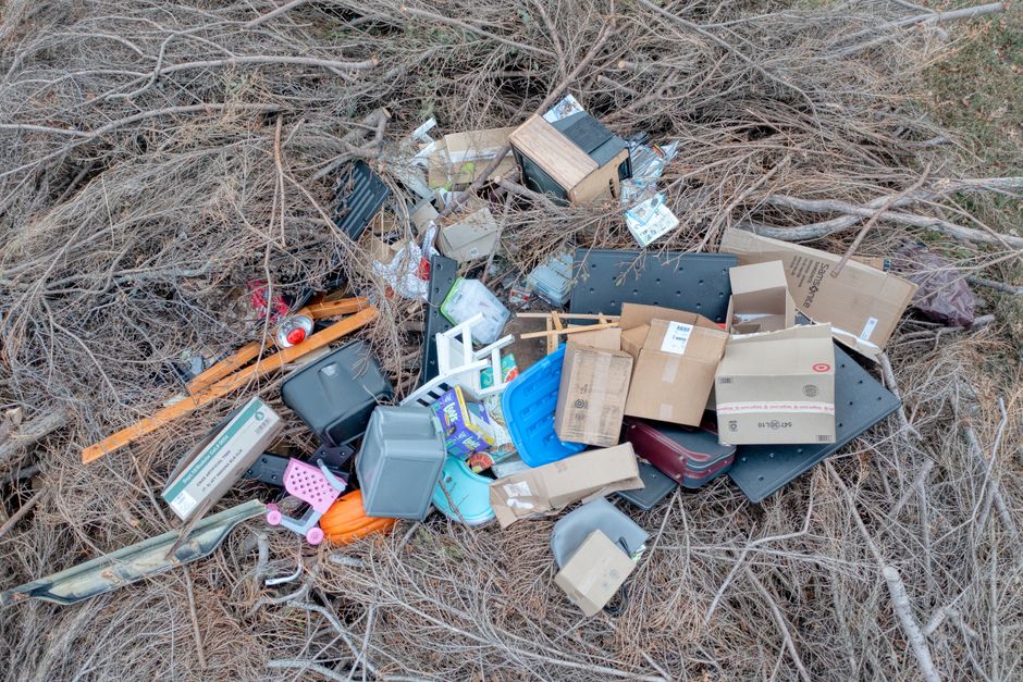Imagem de lixo eletrônico e embalagens descartadas em uma área ao ar livre, evidenciando o problema do descarte incorreto de resíduos tecnológicos.