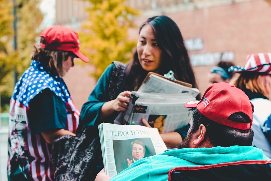 Mulheres participando de uma manifestação ou protesto com bandeiras e cartazes ao ar livre durante o dia de outono.