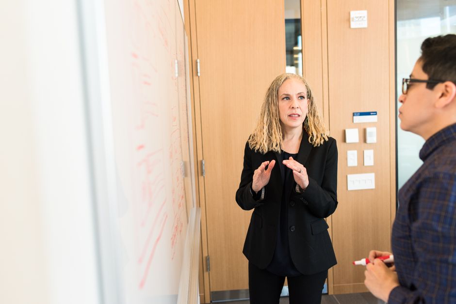 Professora explicando conceitos durante uma reunião de negócios ou aula de capacitação empresarial, com ênfase na comunicação e formação de equipe.