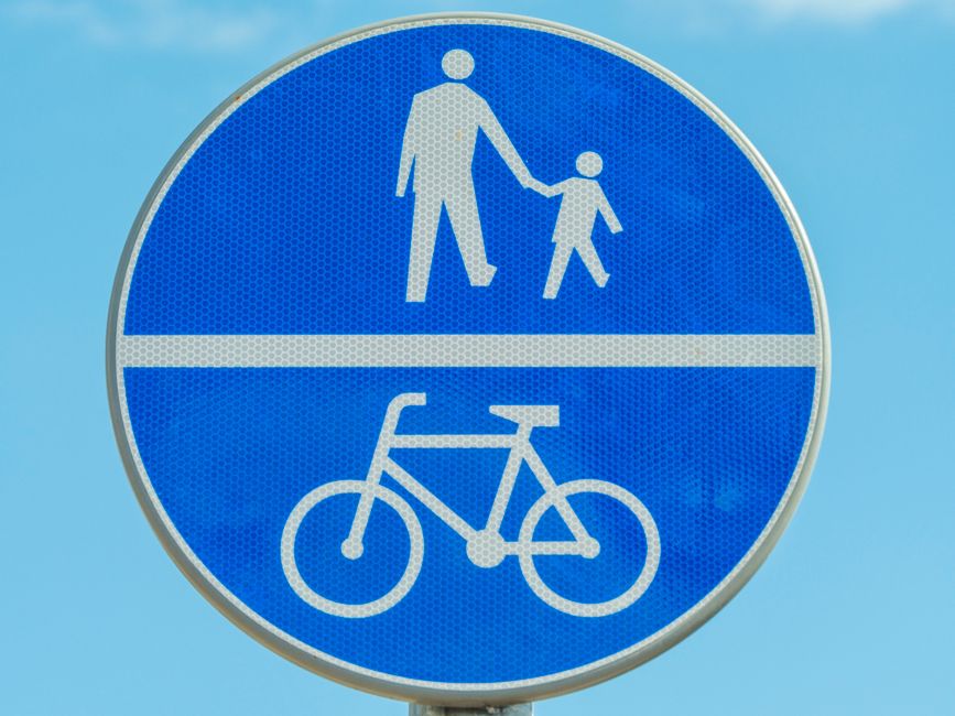 Placa de sinalização que indica separação entre pista para pedestres e ciclistas, promovendo segurança e convivência no trânsito.
