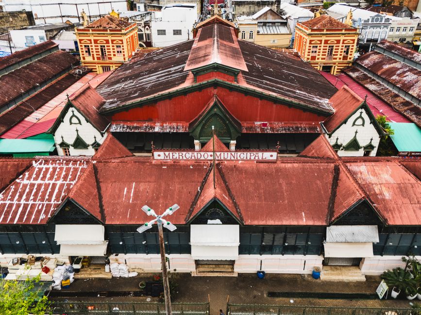 Imagem aérea de um mercado municipal antigo com telhados de zinco, refletindo a história cultural de uma cidade brasileira.