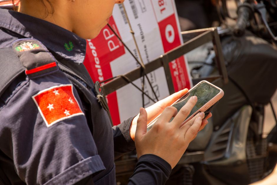 Juíza ou integrante de forças de segurança usando smartphone durante atividade ao ar livre, possivelmente em operação ou inspeção.