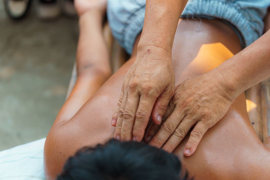 Profissional realizando massagem terapêutica em pessoa, focando no bem-estar e cuidado com a saúde física.