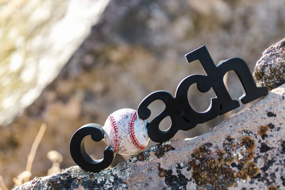 Imagem de uma bola de beisebol apoiada na palavra 'cash' em um ambiente natural ao ar livre, simbolizando o crescimento financeiro ligado ao esporte.