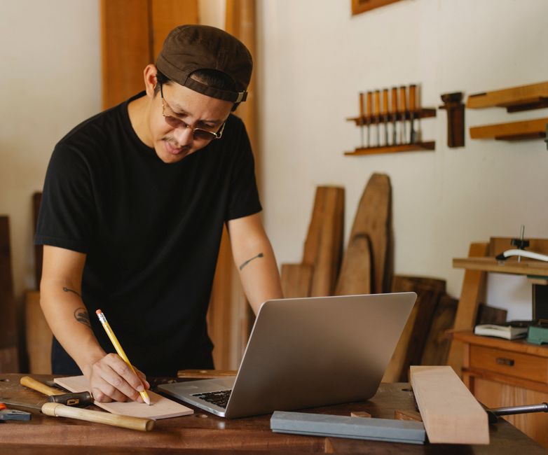 Artesão ou marceneiro trabalhando em seu ateliê, focado na criação e processamento de madeira ou objetos de carpintaria.