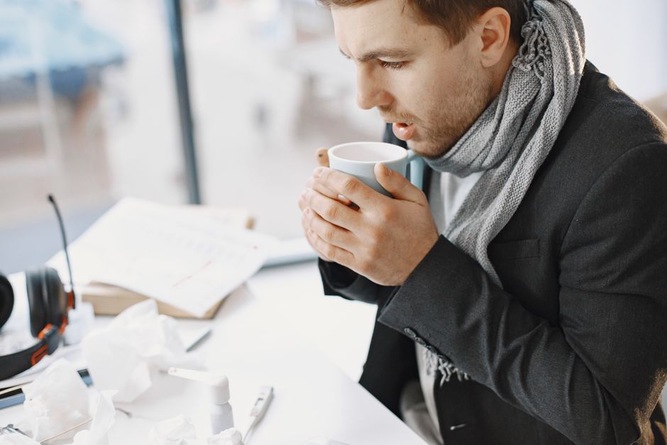 Pessoa trabalhando em ambiente de escritório enquanto toma uma xícara de café, evidenciando rotina matinal e produtividade no trabalho.