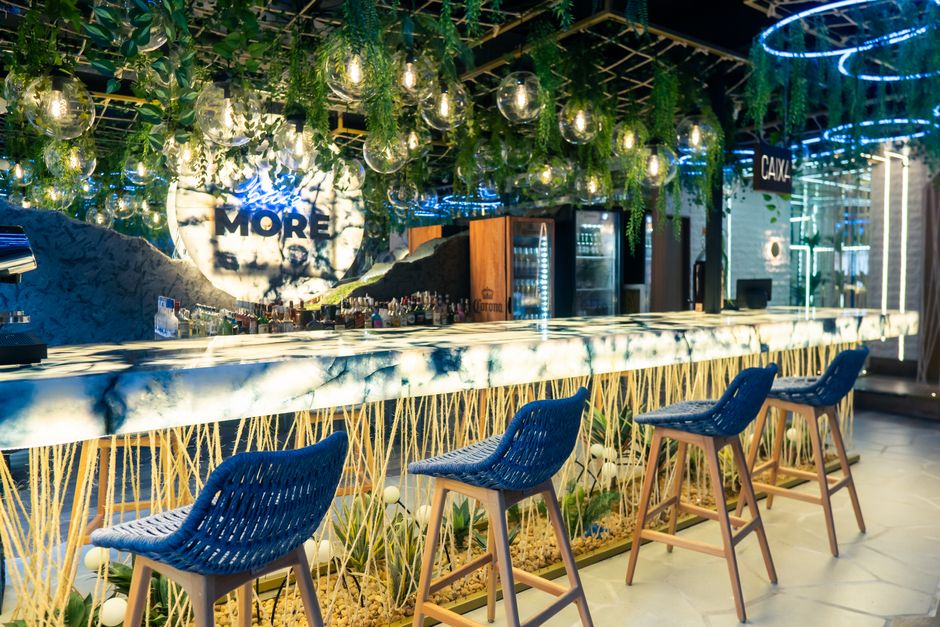 Bar sofisticado com decoração moderna e iluminação ambiental, ideal para ambientes de lazer e convivência.