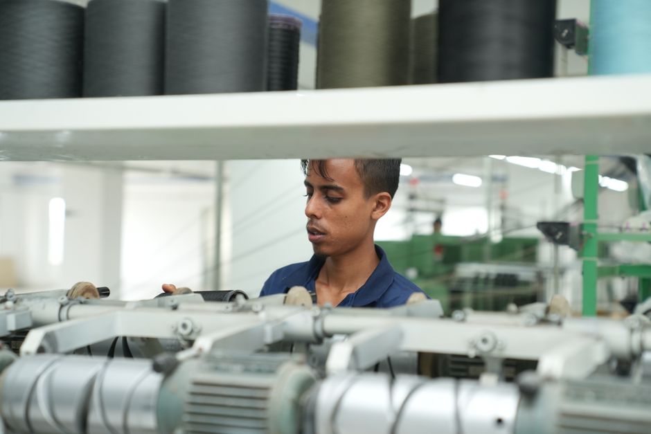 Homem analisando máquinas industriais em um ambiente de produção, destacando o tema de manufatura e tecnologia.
