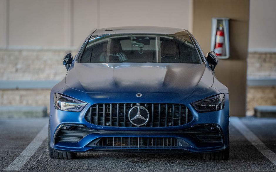 Imagem de um carro Mercedes-Benz azul em destaque, estacionado em ambiente urbano ou garagem, com foco no veículo de luxo e design moderno.