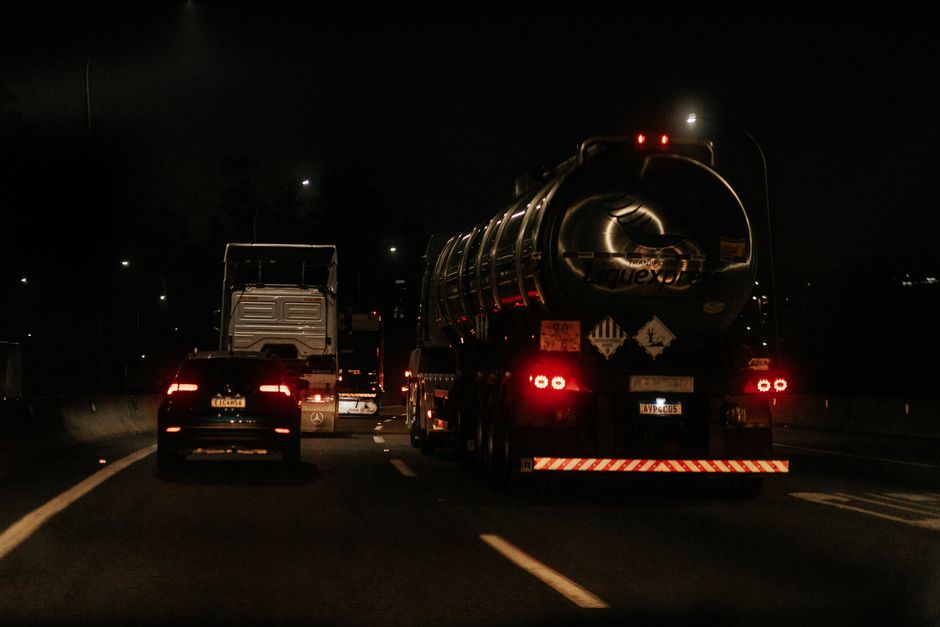 Imagem de uma rodovia à noite com veículos de transporte de líquidos, destacando a circulação noturna e a segurança nas estradas.