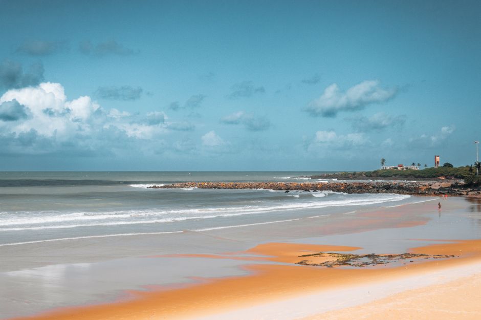 Praia tranquila com céu nublado e mar calmo, ideal para momentos de relaxamento e lazer à beira-mar.