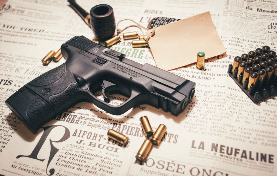 Imagem de uma arma de fogo sobre jornais, associada a temas de violência e segurança pública.