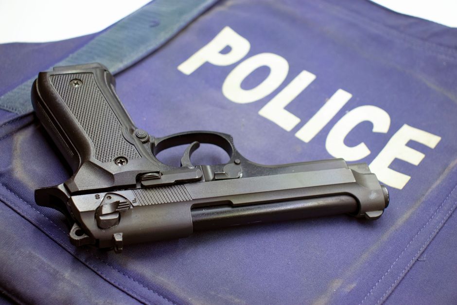 Revólver e colete à prova de balas em uma cena que remete à segurança policial e investigação criminal.