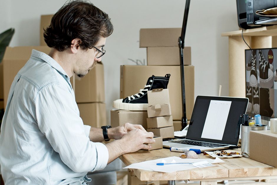 Homem organizando produtos e planejar negócios em um ambiente de trabalho com caixas e computador.
