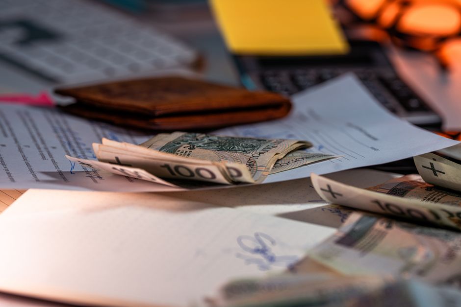 Imagem de uma mesa de trabalho com papéis, dinheiro e objetos de escritório, ilustrando temas relacionados à gestão financeira e planejamento de gastos.