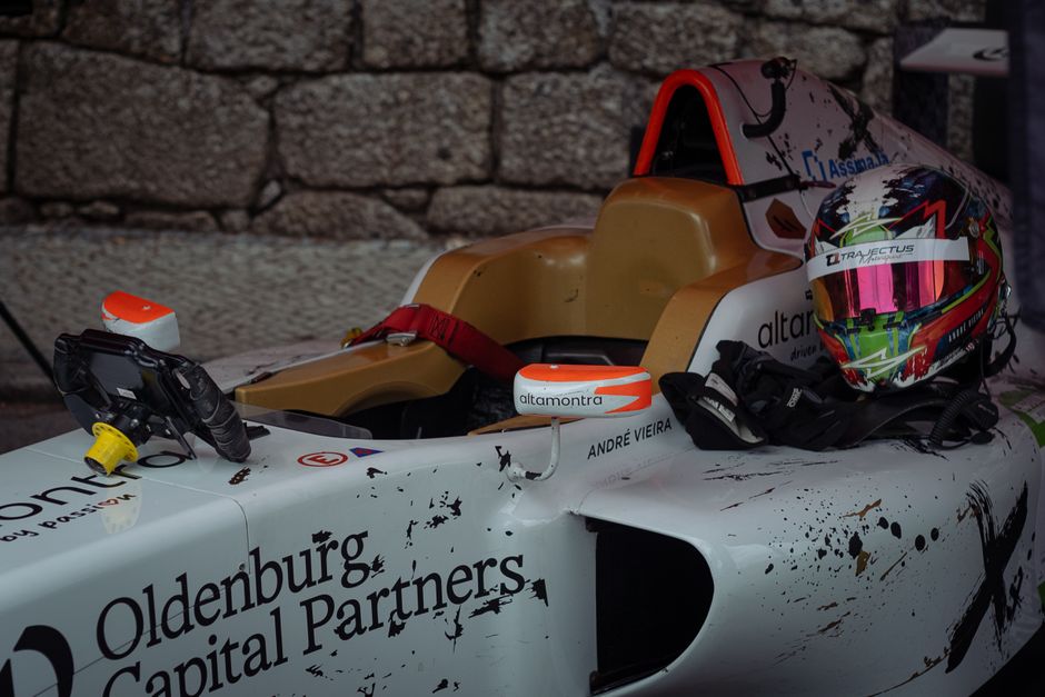 Imagem de um carro de corrida de Fórmula 1 com um capacete de piloto ao lado, preparado para uma corrida ou evento esportivo.