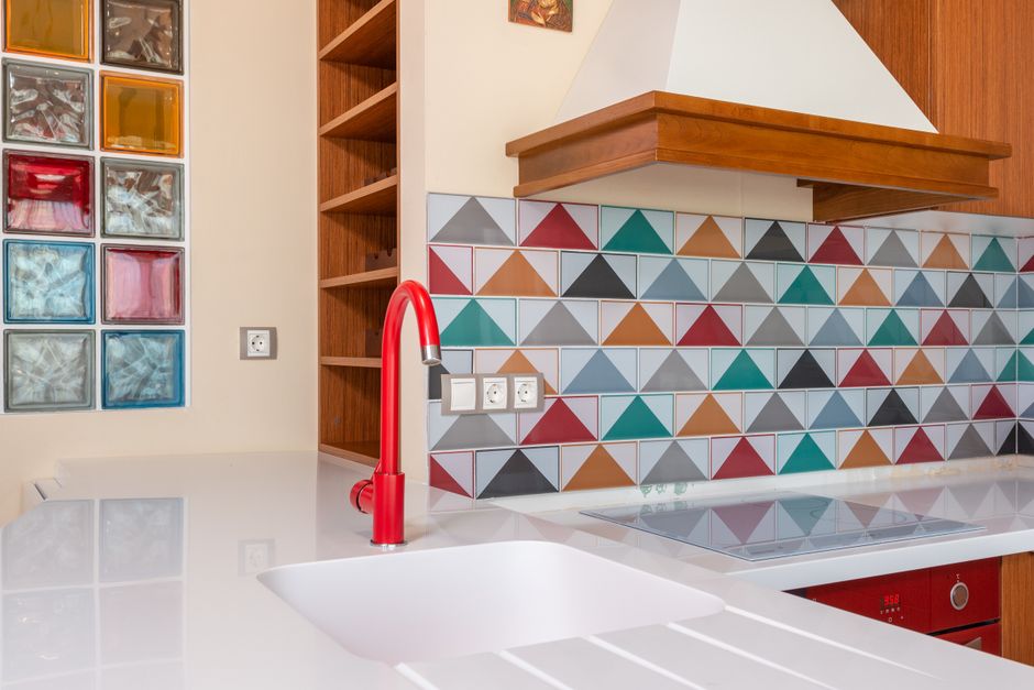 Cozinha moderna com revestimento de azulejos coloridos e detalhes em madeira, destacando um espaço aconchegante e bem planejado para preparação de alimentos.