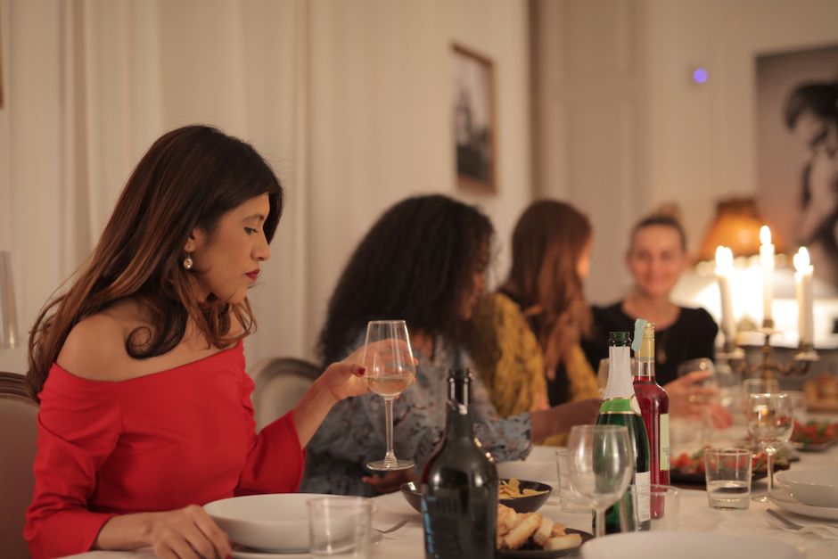 Mulheres reunidas em uma celebração elegante, conversando e aproveitando uma noite social em um jantar sofisticado.