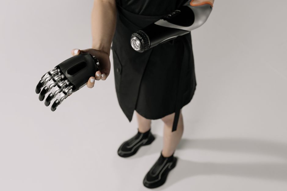 Pessoa segurando uma garrafa de vidro e uma prótese de braço robótica, sugerindo inovação e tecnologia humana.