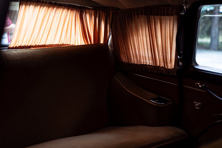 Interior de um veículo clássico com cortinas de tecido na janela, transmitindo uma atmosfera vintage e acolhedora.