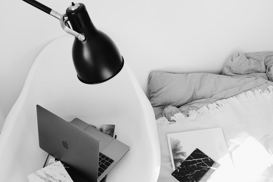 Imagem de um espaço de trabalho organizado na cama, com laptop, livros e luminária, ideal para abordar temas de produtividade e home office.