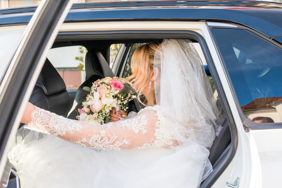 Noiva em um carro de luxo celebra seu casamento, simbolizando a felicidade e o início de uma nova fase da vida.