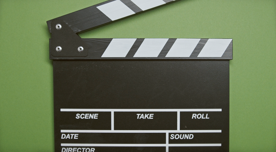 Imagem de um diretor de cinema segurando um quadro de roteiro, simbolizando planejamento criativo e produção audiovisual.