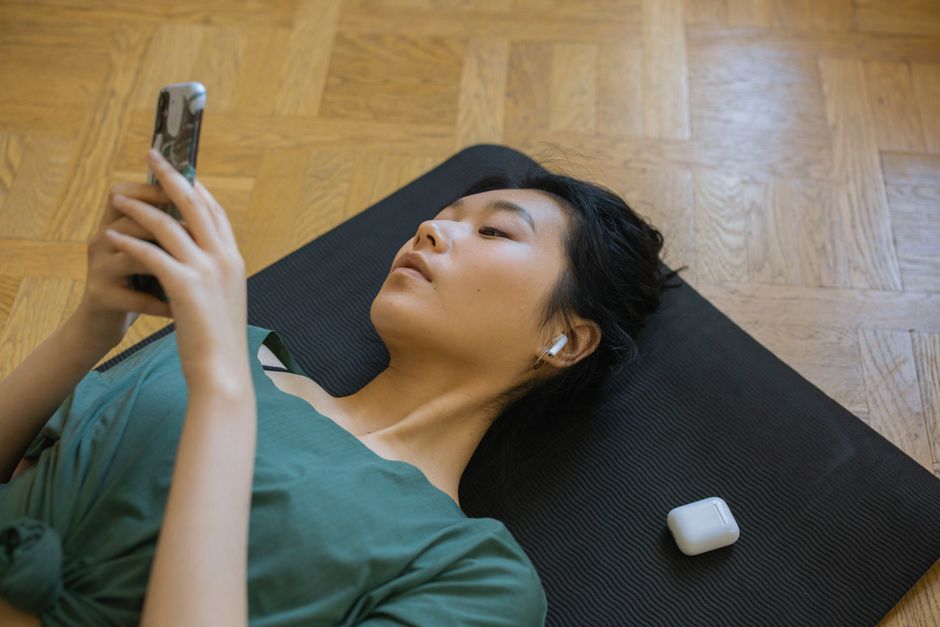 Mulher descansando e usando fones de ouvido, com foco em bem-estar e relaxamento após atividade física ou trabalho.