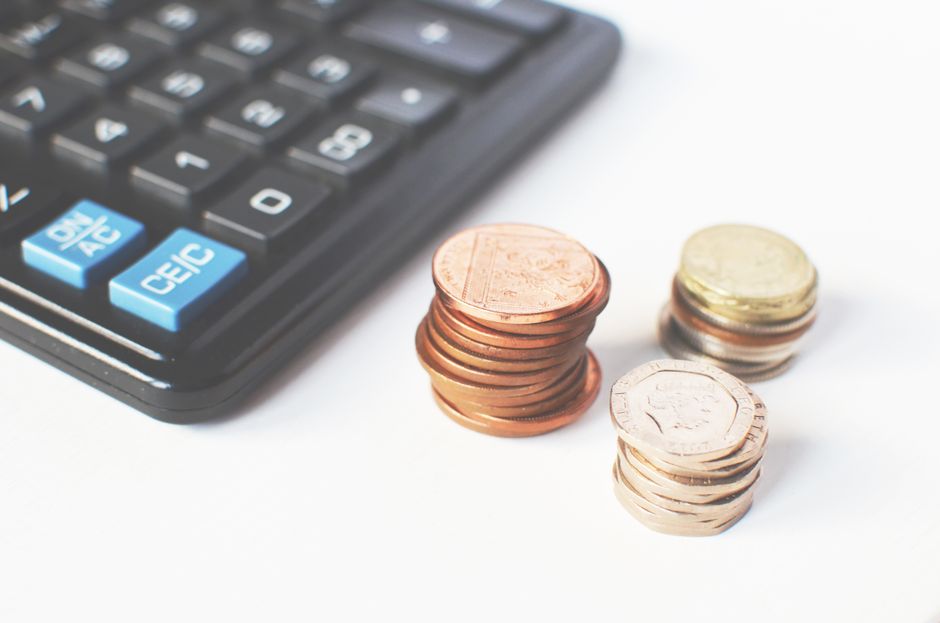 Imagem ilustrativa de controle financeiro e gestão de despesas com moedas e calculadora, ideal para artigos sobre planejamento financeiro pessoal ou empresarial.