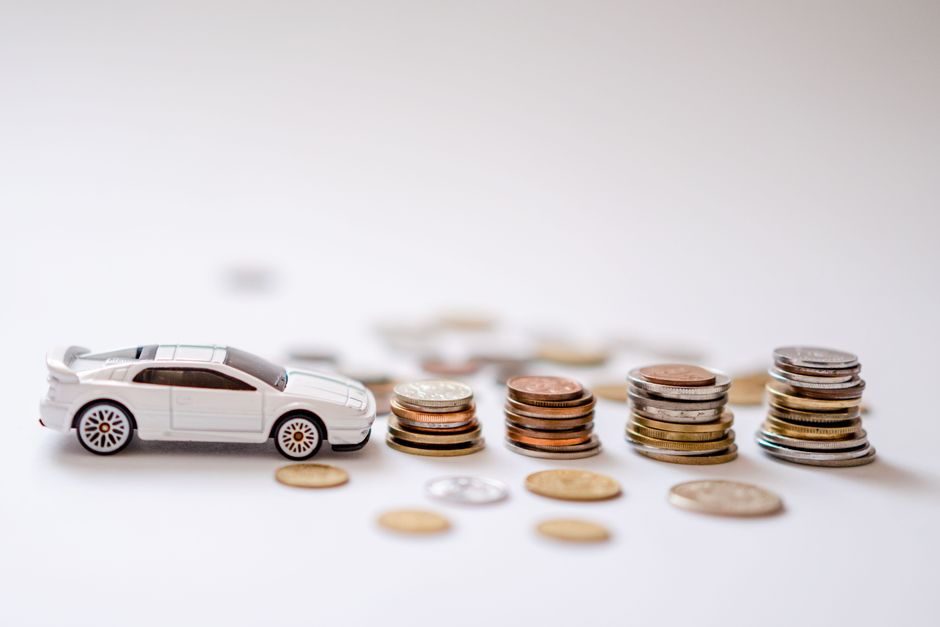 Imagem ilustrativa representando gestão financeira, com um carrinho de brinquedo ao lado de pilhas de moedas de diferentes valores, simbolizando controle de gastos e economia.