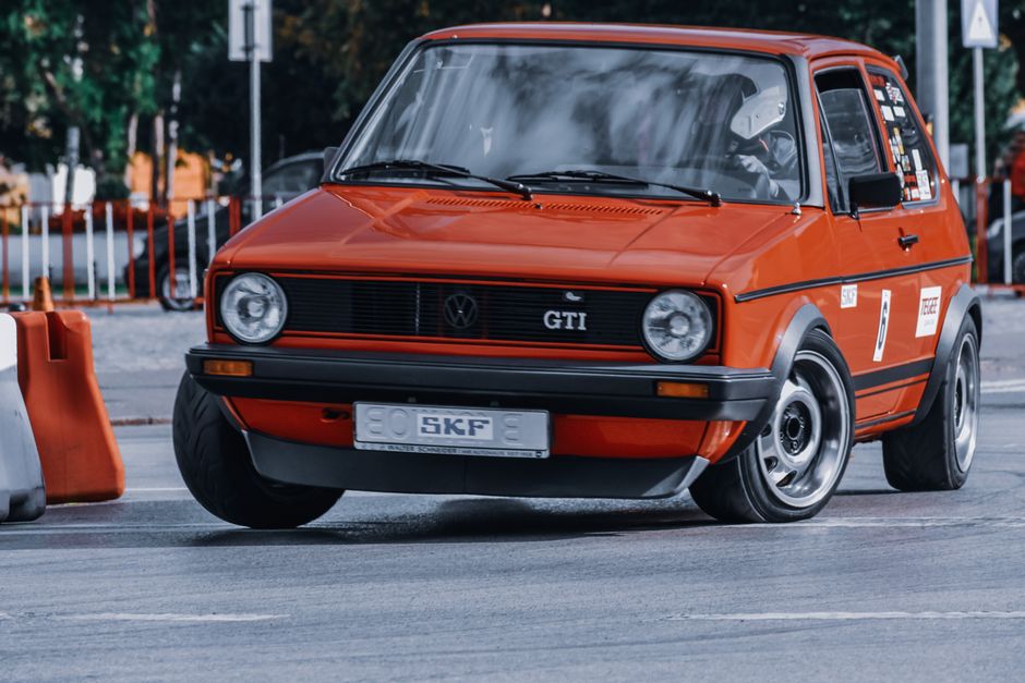 Carro de corrida clássico Volkswagen Golf GTI vermelho em uma pista de evento automotivo.