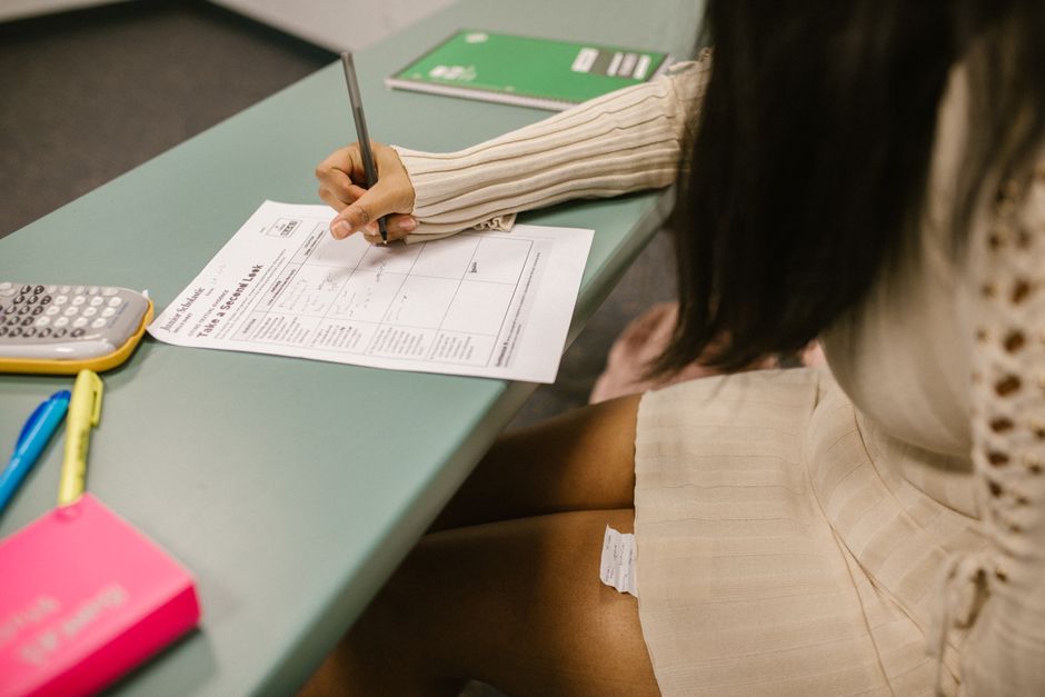 Pessoa preenchendo uma declaração de imposto de renda em um ambiente de escritório, com materiais de escritório ao redor.