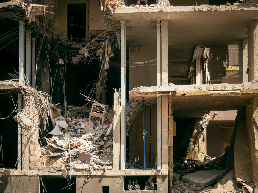 Imagem de uma construção ou prédio em ruínas, destacando os efeitos de destruição ou abandono na estrutura.