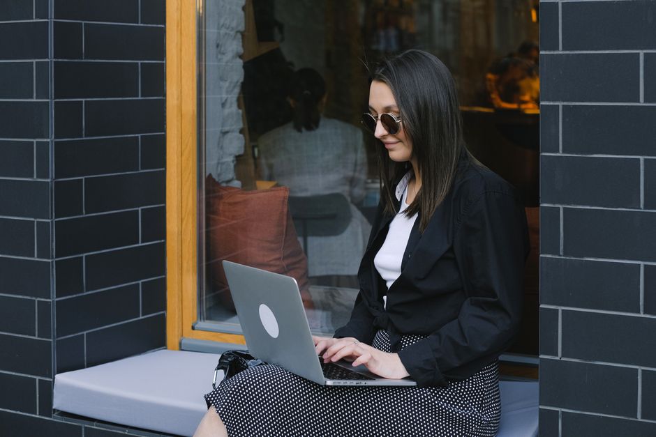 Jovem trabalhando de forma freelance usando um laptop em um ambiente externo com estilo contemporâneo.